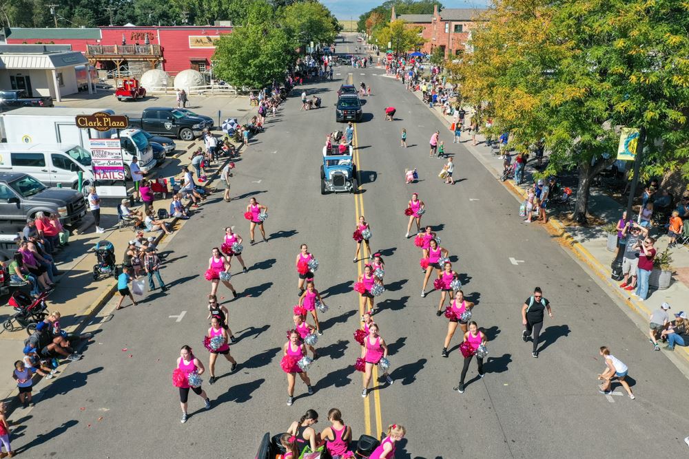 Cheerleaders in pink outfits perform in a town parade on a sunny day in the Miners Day parade.