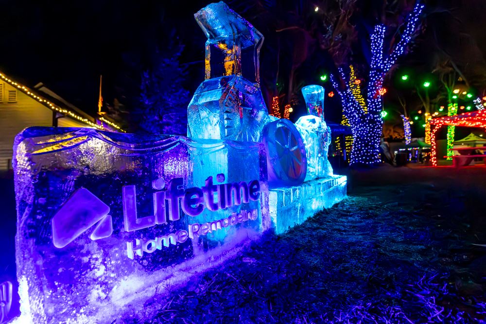 Illuminated ice sculpture of a train with vibrant holiday lights.