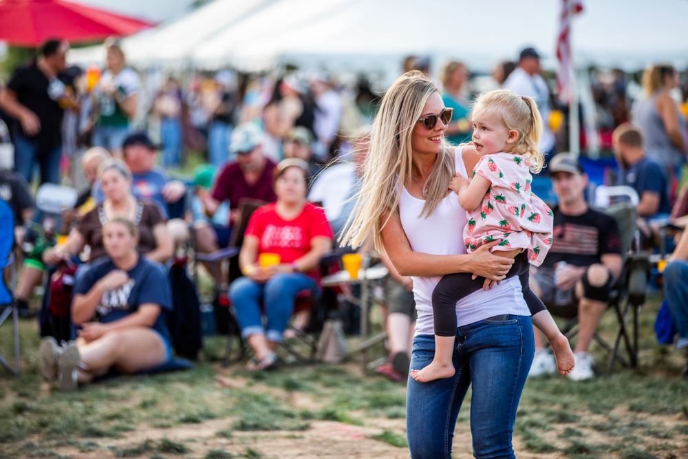 A wwoman holding a child infront of a crowd